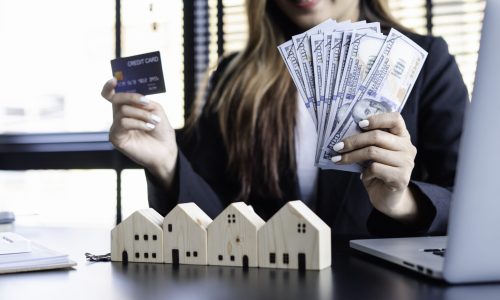 Asian business women hold credit cards and dollar cash to invest in purchases. Or selling housing projects in project offices, project offices, investment ideas and buying houses.