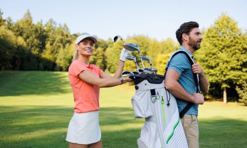 Golf Partnerships: Woman Picks Club from Companion's Bag