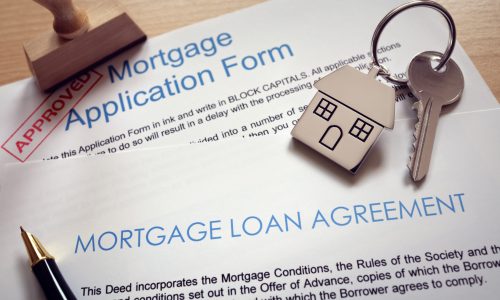 Mortgage loan agreement application with  key on house shaped keyring